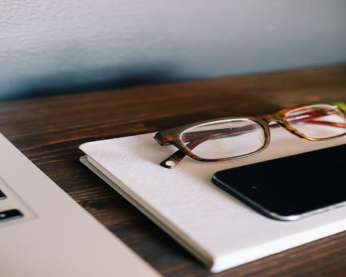 a notebook and a phone placed properly on a wooden desk